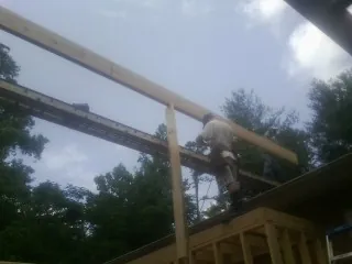 Carpenter setting a ridge beam over a new addition frame — Ice Dam Removal by Roofing Brothers in Harrah