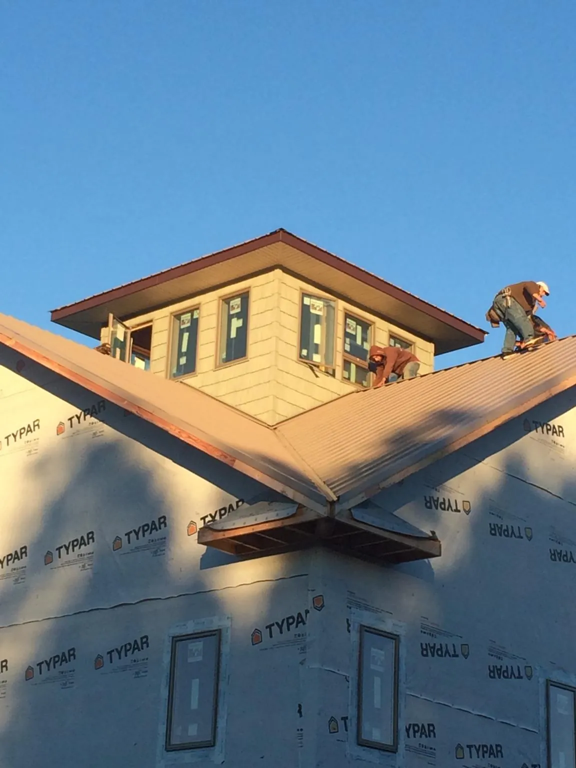 Roofers working around a rooftop cupola on a new metal roof at sunset — Roof Waterproofing in Harrah by Roofing Brothers